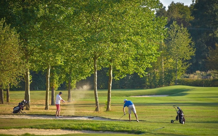 Golfers playing among trees at Golf de Château de Chailly