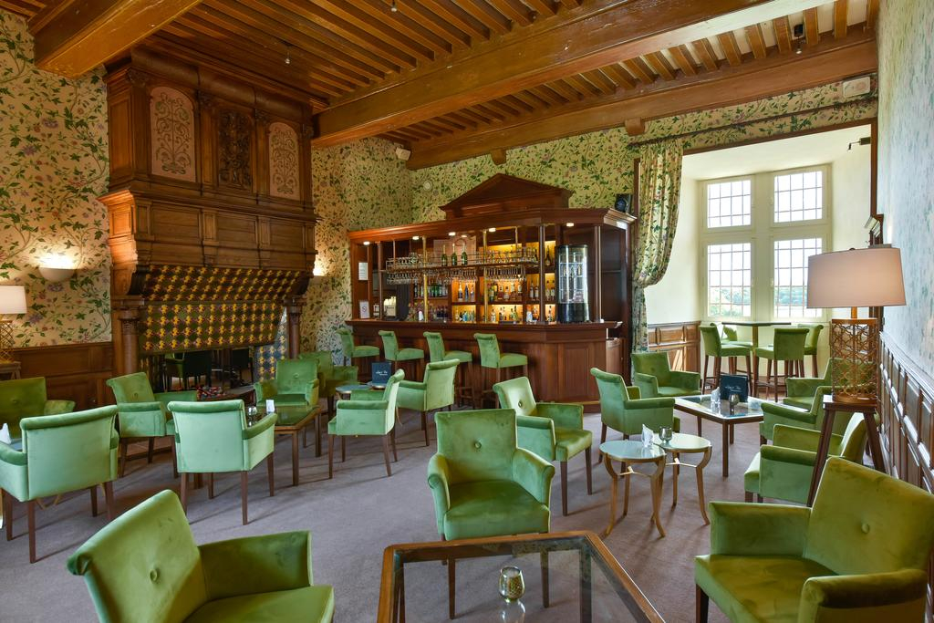 Hotel bar lounge at Château de Chailly with green chairs and timber ceiling