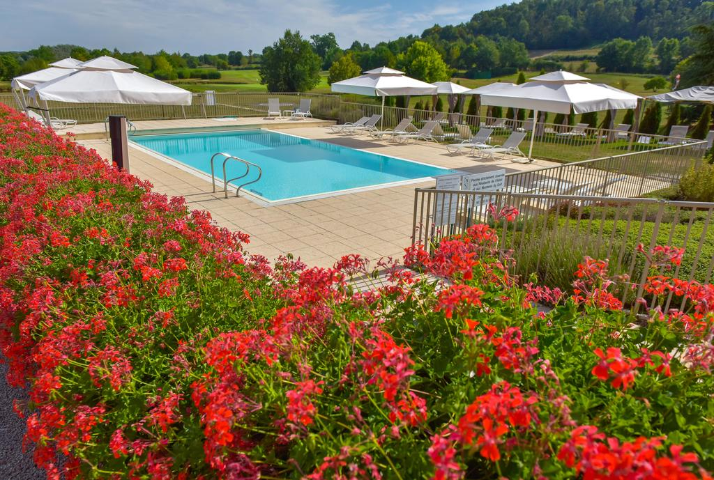 Outdoor pool at Château de Chailly with red flowers and white parasols