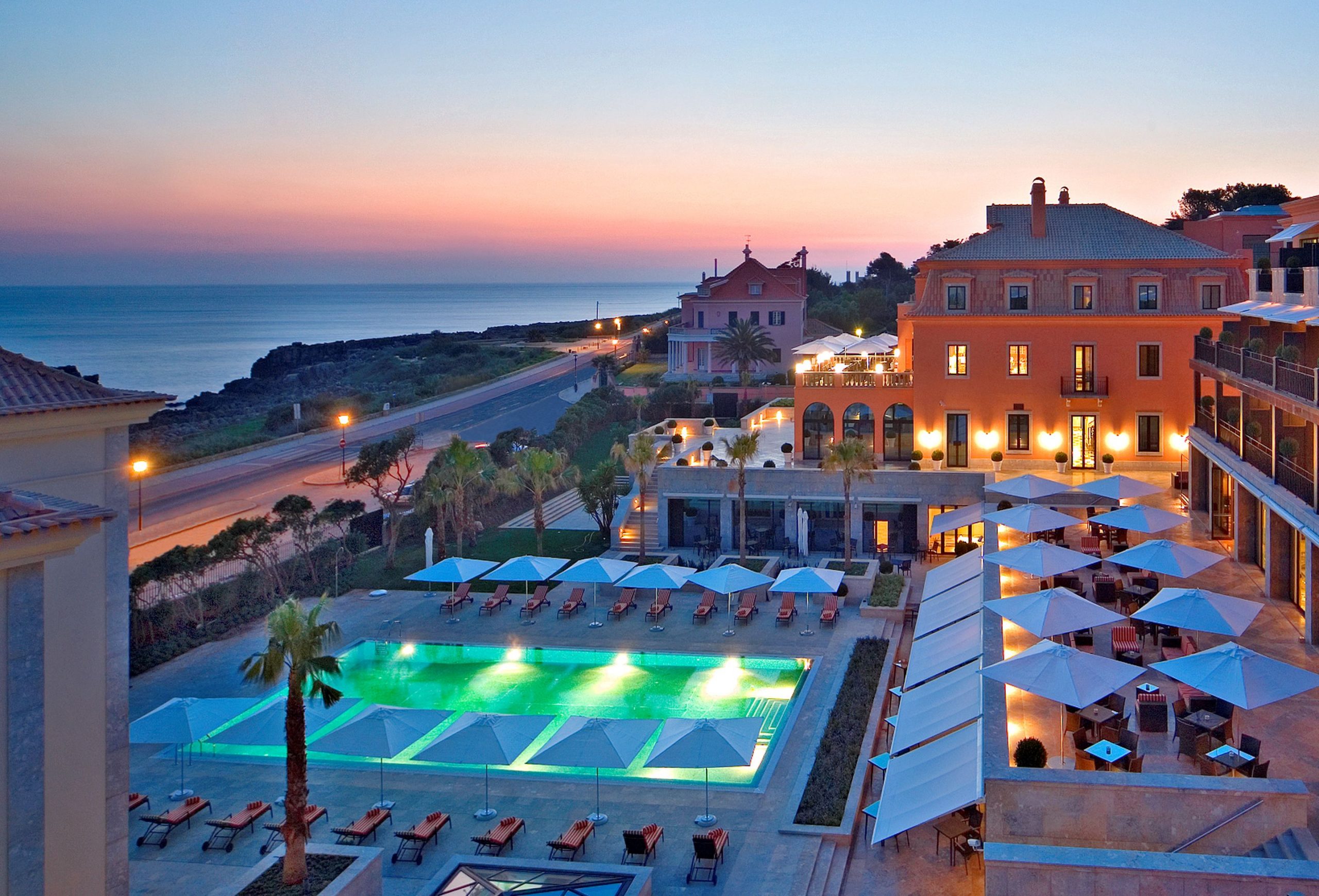The Grande Real Villa Italia Hotel, Cascais, Portugal, lit up at sunset.
