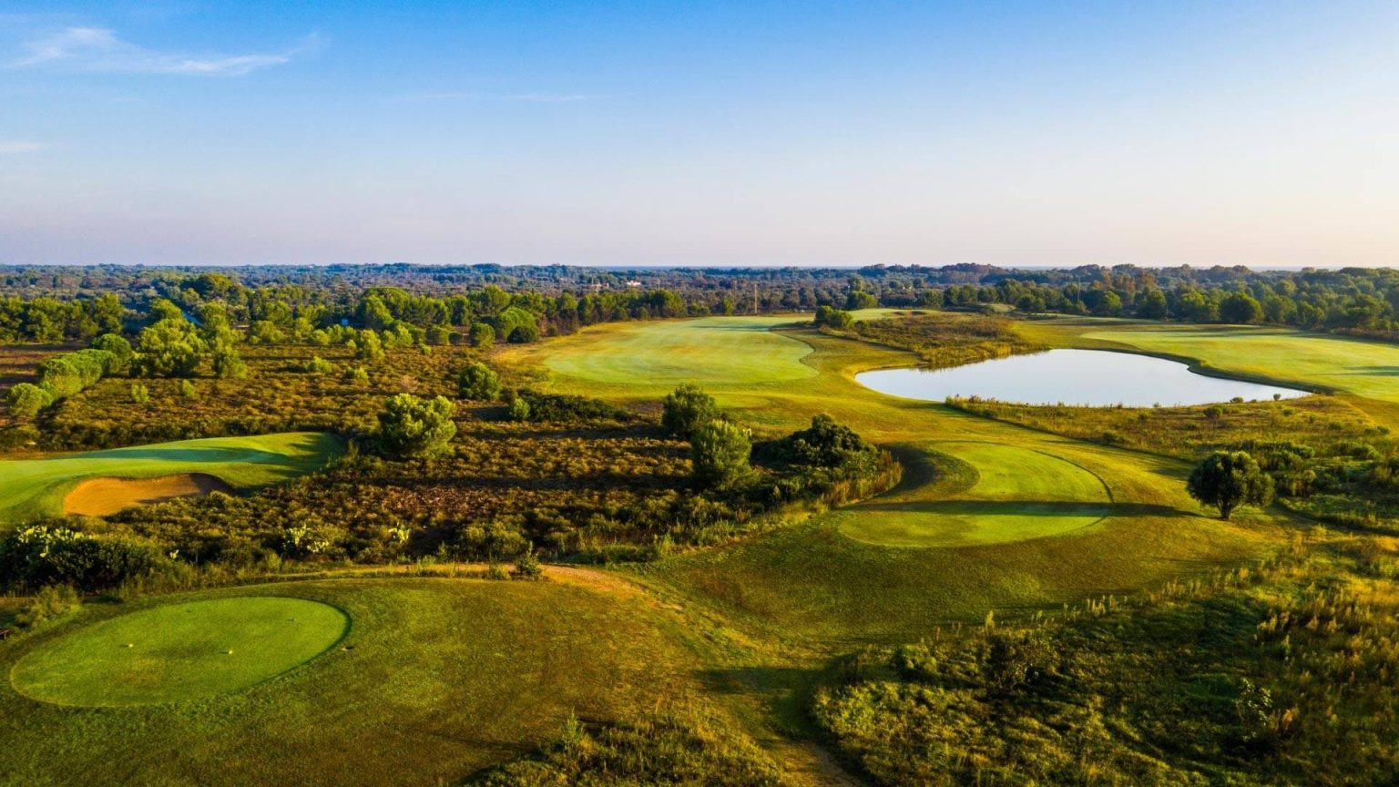 Aerial view of a green, bunkers and water on the Acaya golf course, Puglia