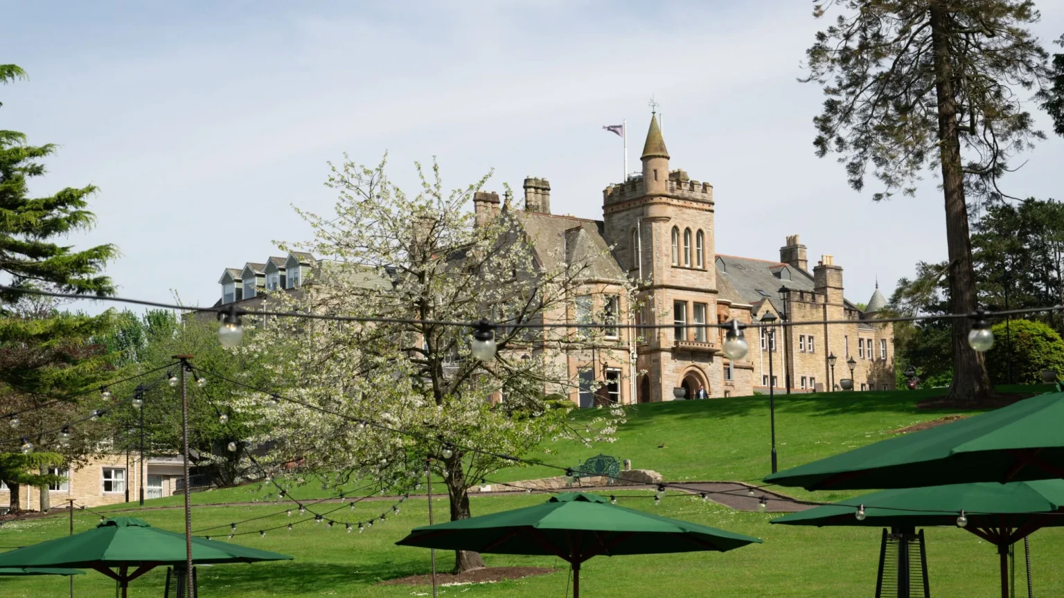 The Culloden mansion viewed across the gardens, with parasols and cherry blossom