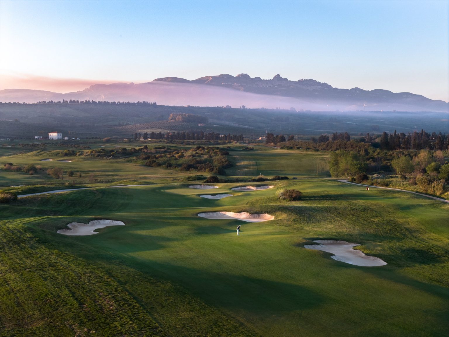 Aerial view of the Verdura golf course with the Sicilian hills and morning mist beyond