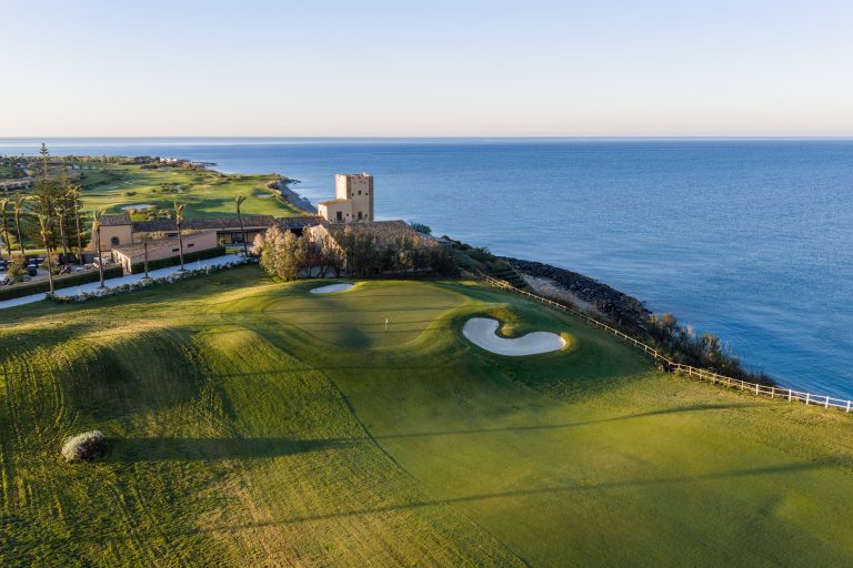 A coastal golf hole at Verdura, Sicily, with a stone watchtower above the Mediterranean