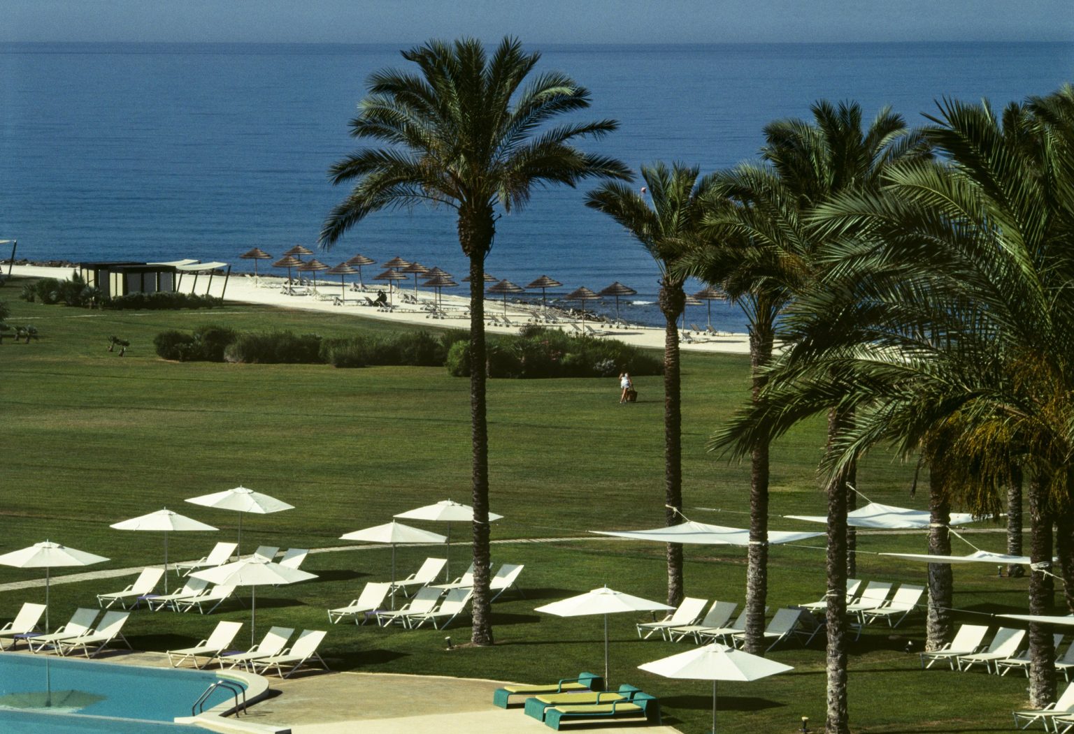 Lawns, palms and sun loungers leading to the sea at Verdura Resort, Sicily
