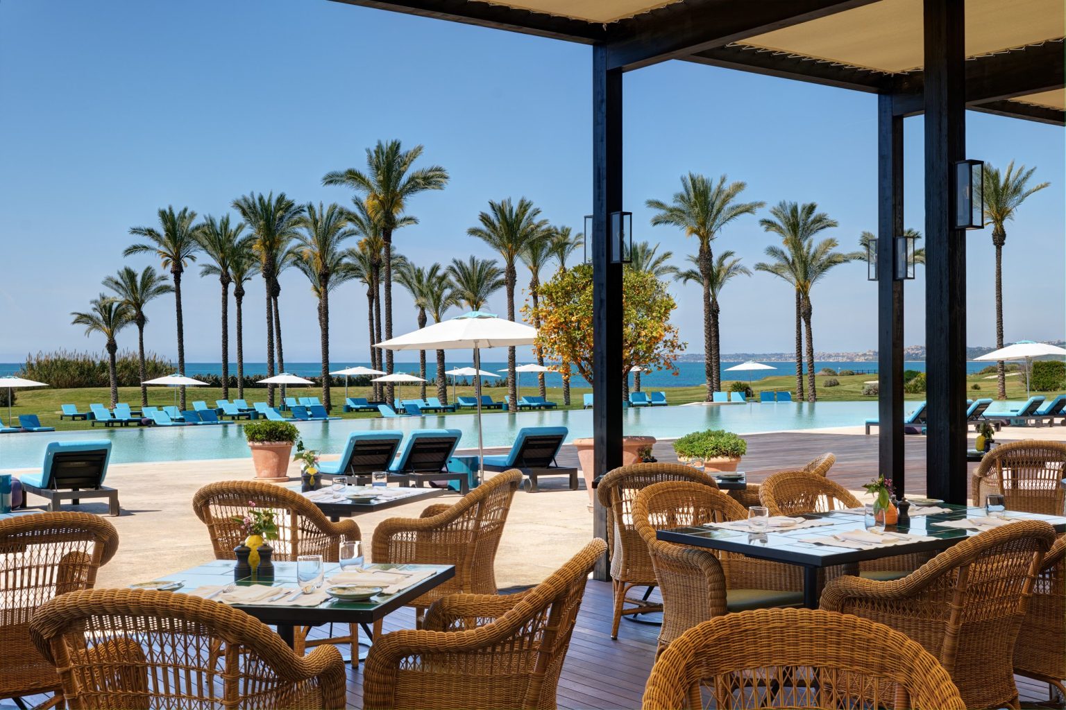 The Buongiorno restaurant terrace at Verdura Resort, with palms and poolside loungers