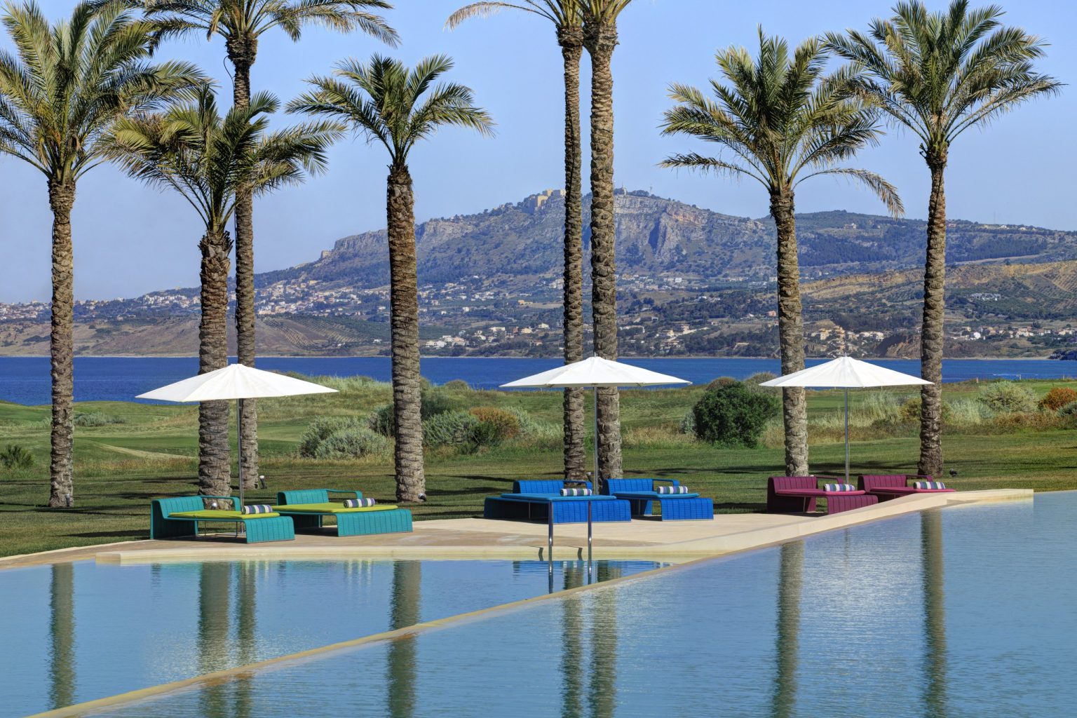The infinity pool at Verdura Resort, framed by palms with the sea and mountains beyond